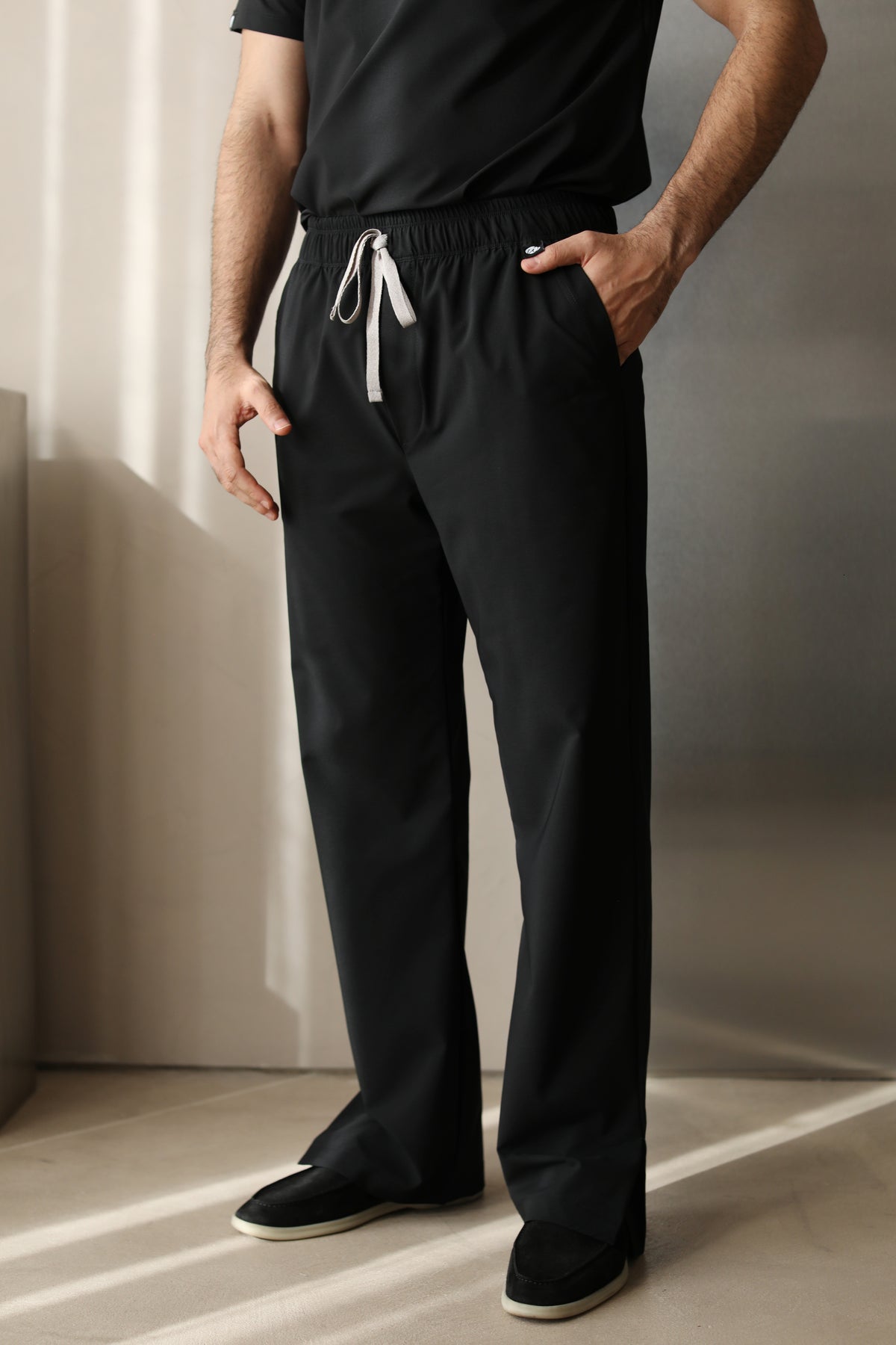 Vista frontal de un hombre usando Harry Negro W&C Shield™ pantalón, mostrando el corte de pierna recta, la cintura con cordón y los bolsillos laterales.